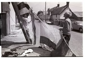 Men putting up large flags for the Jubilee by James Ravilious