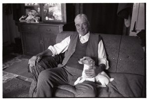 Mr Crocker seated with his dog by James Ravilious
