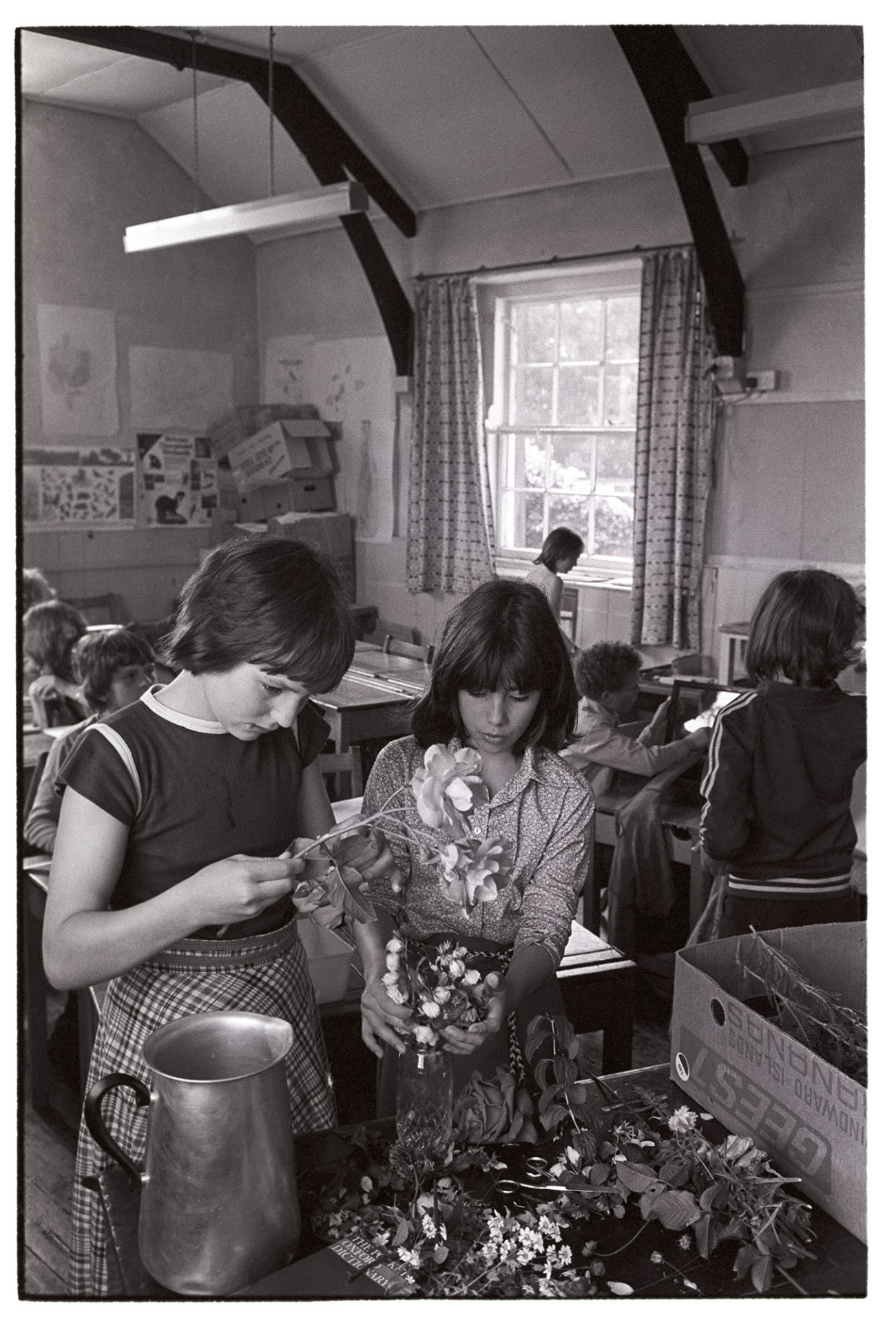 Children in class, arranging flowers.
[Two girls in a classroom arranging flowers at Blue Coats School, Torrington. Other children are working in the background.]