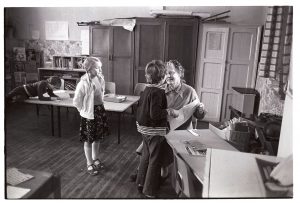 Teacher helping children with their work by James Ravilious