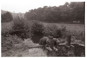 Men repairing a wooden sluice-gate at Head Mill by James Ravilious