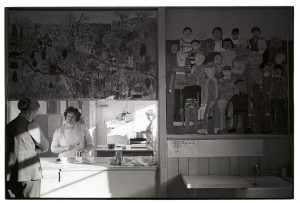 Teacher and dinner lady chatting in the school canteen by James Ravilious