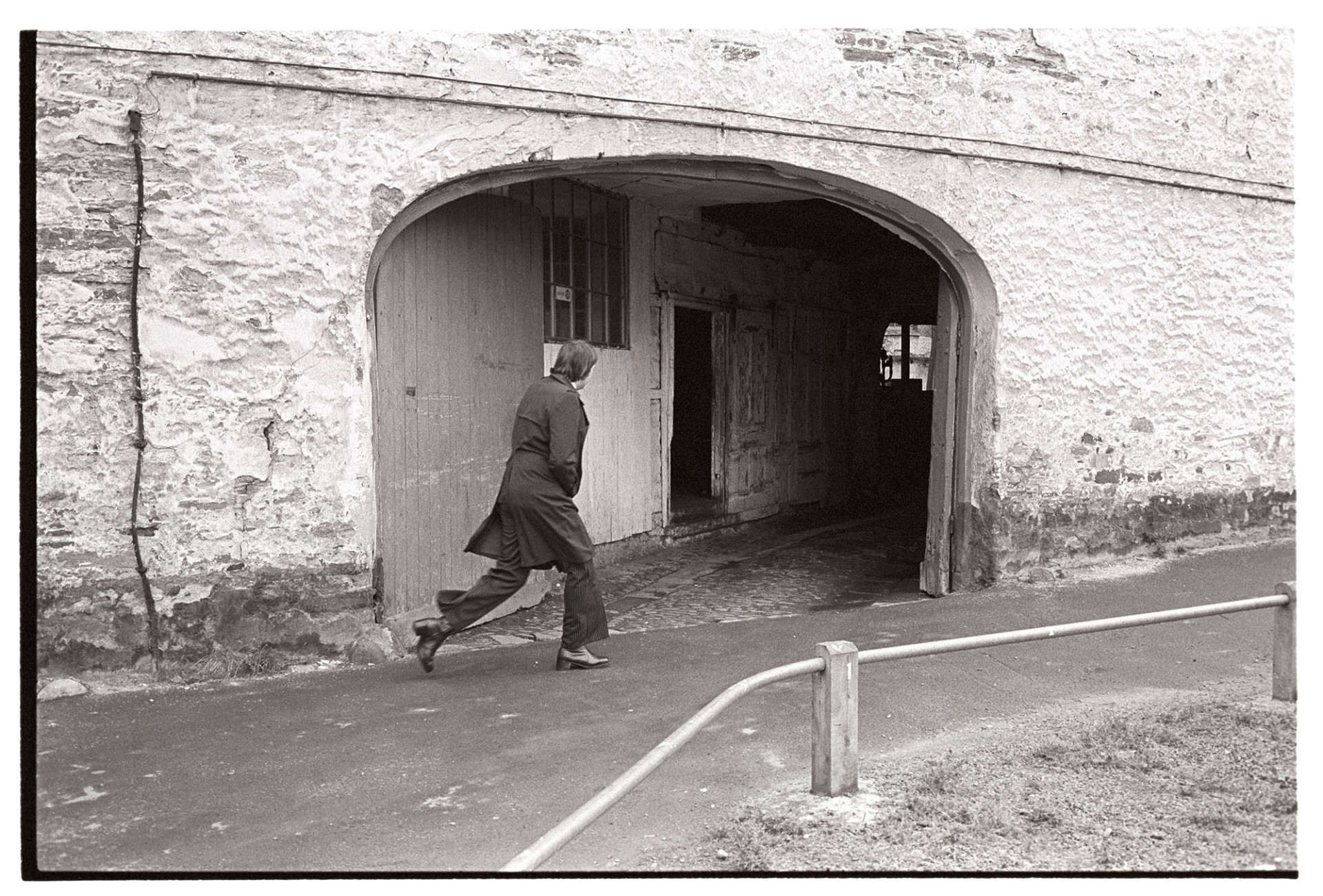 Entrance to factory, now site of new library, records office Doorway. 
[A man walking past the arched entrance to a factory in Tuly Street, Barnstaple. The site later became the Barnstaple Library and North Devon Record Office.]