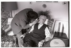 Dr Paul Bangay checking the ears of an elderly patient by James Ravilious