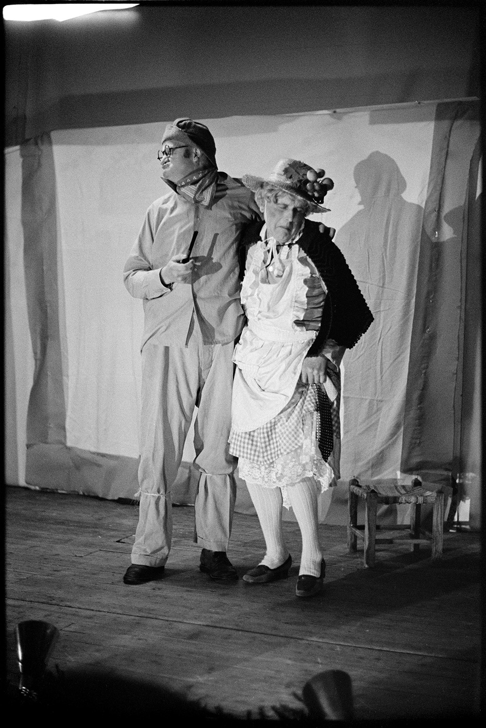 Christmas entertainment in village hall, singing and dance, short plays.<br />
[George Keen, on the left, and John Tucker, on the right, in fancy dress on stage at High Bickington village hall. They are performing a short play for Christmas entertainment.]