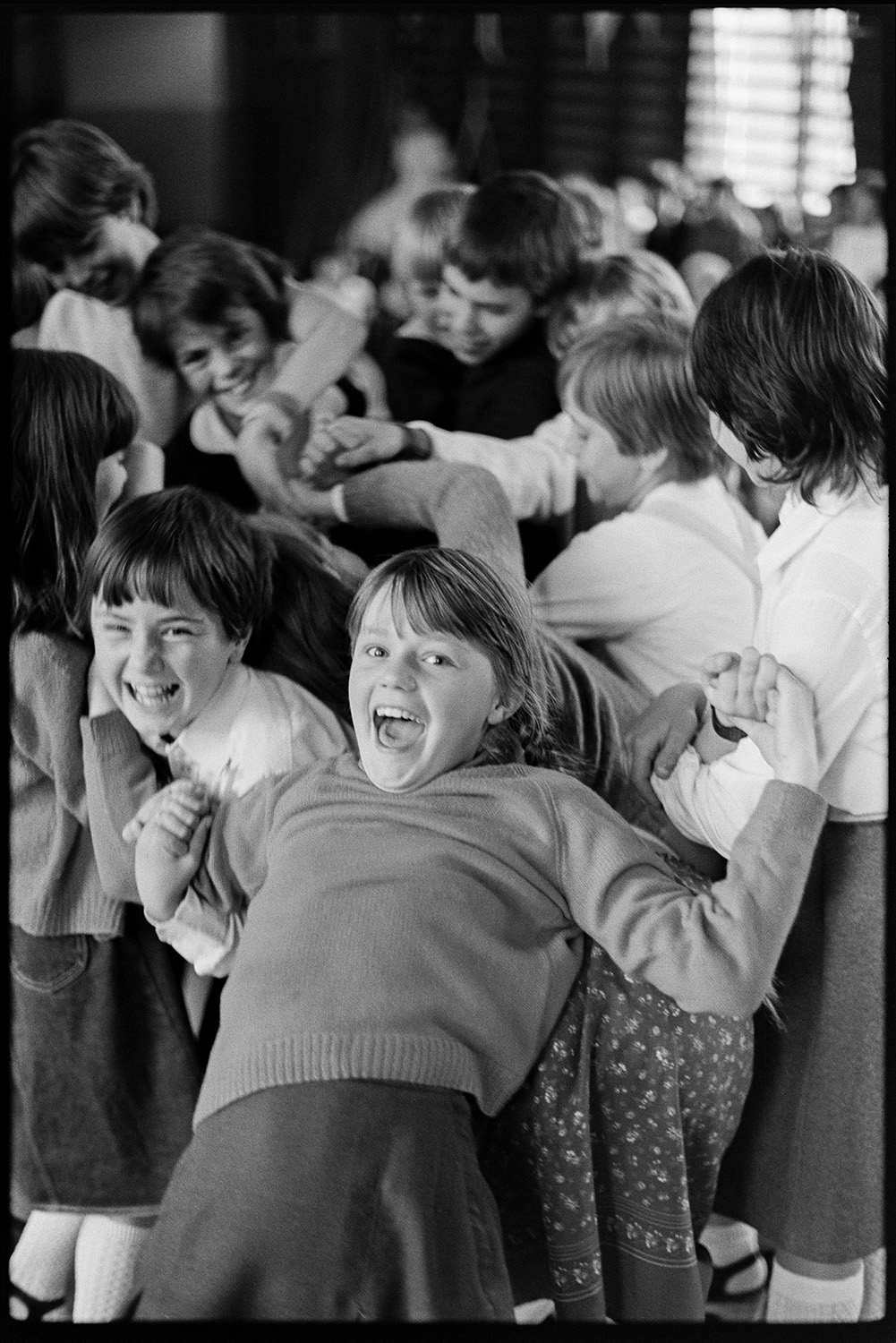 Schoolchildren singing, dancing with folk duo. 
[Children laughing and playing in a school hall in Barnstaple at a folk workshop being run by folk duo Sam Richards and Tish Richards.]