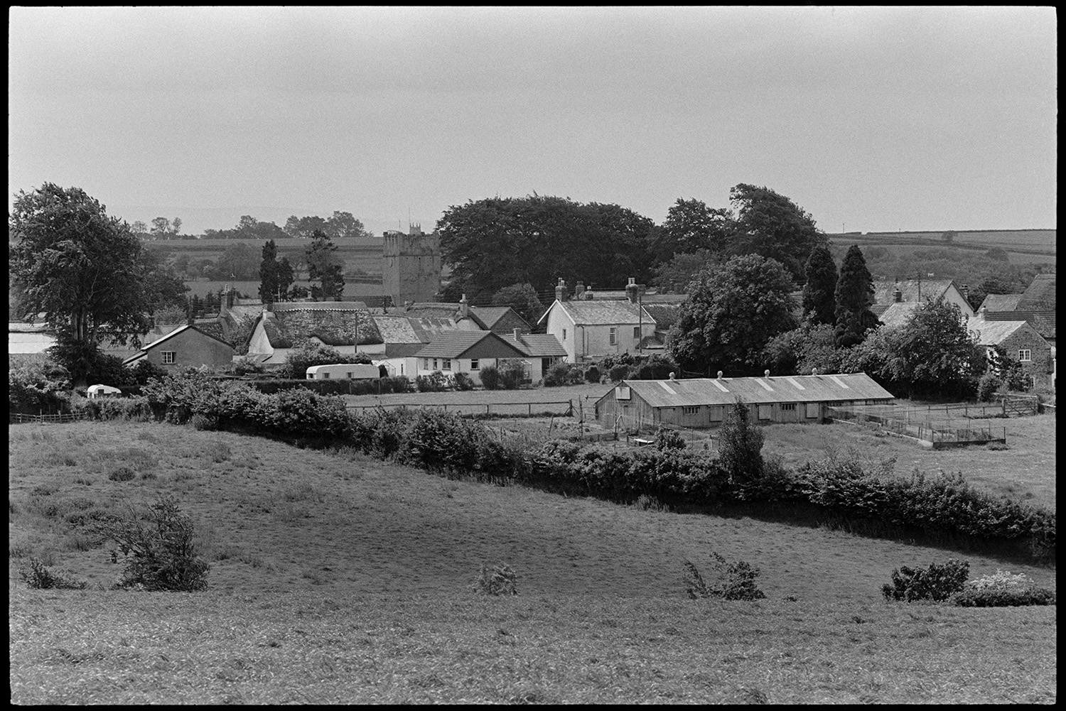 A view of Dolton with fields, houses and the church tower. James Ravilious took this image as a test shot to experiment with a new lens.