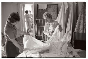 Viewing household linen at a sale by James Ravilious