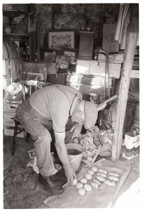 Lloyd Mitchell selecting potatoes for the flower show by James Ravilious