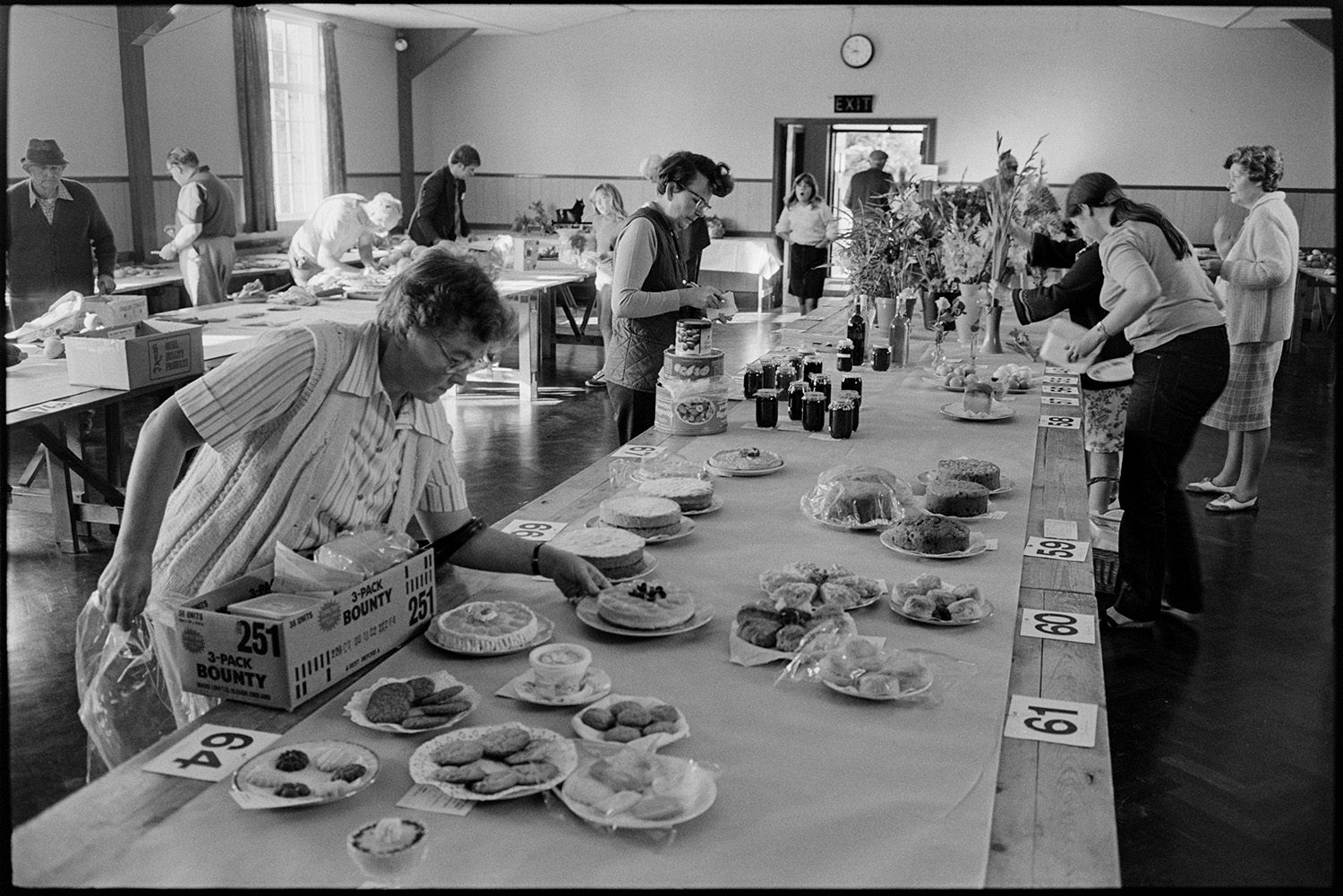 Preparing vegetables and flowers, flower show, boot of car with vegetables, chrysanthemums. 
[Men and women arranging their entries of Flowers, jams and cakes at Dolton Flower Show in Dolton Village Hall.]