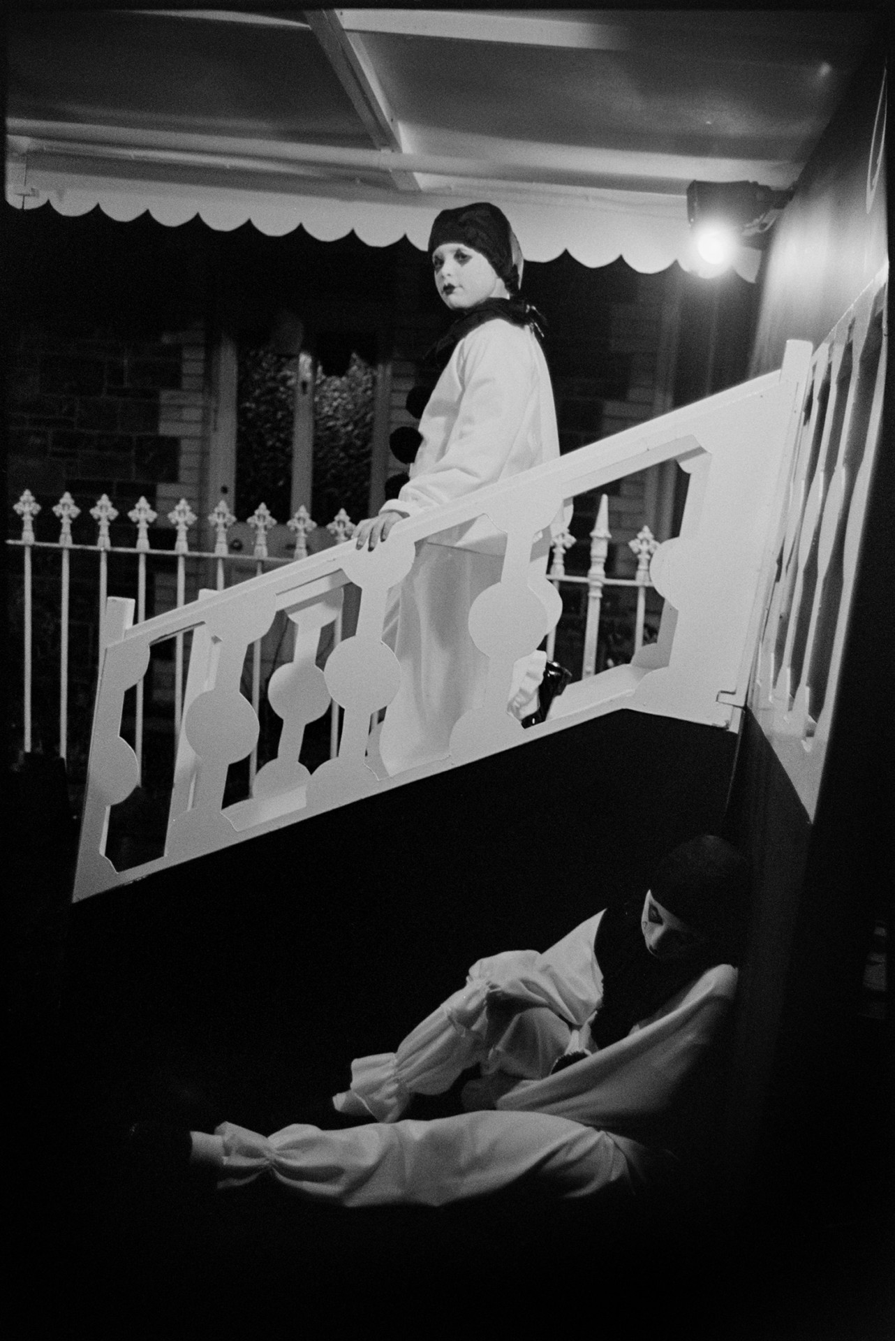 Carnival parade at night floats. 
[Two people dressed as Pierrot characters on a carnival float at Dolton Carnival.]