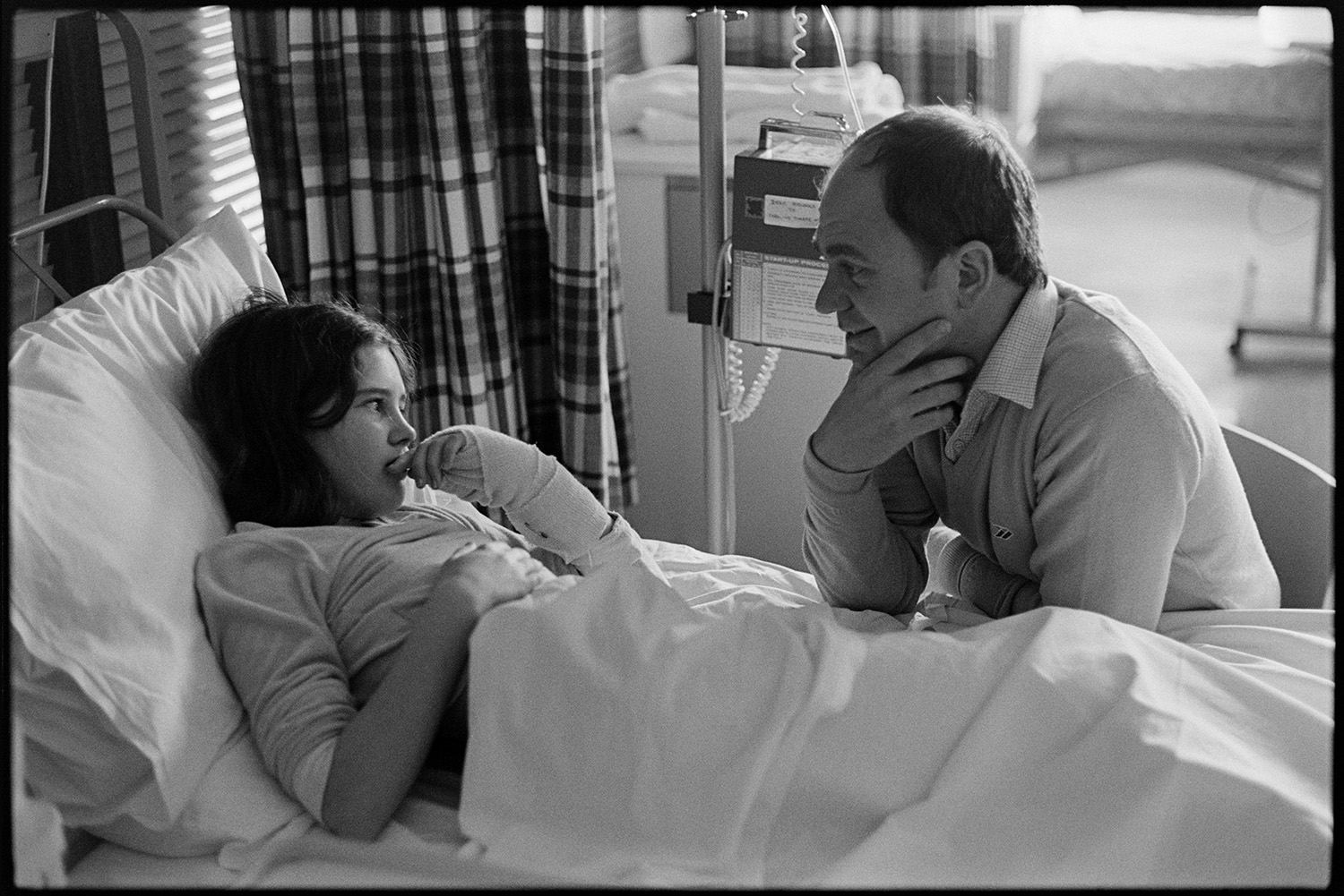Hospital children's ward, eating, father visiting daughter in bed, Sister and Doctor, bed making. 
[A father talking to his daughter who is in a hospital bed on the Children's Ward at Barnstaple General Hospital.]