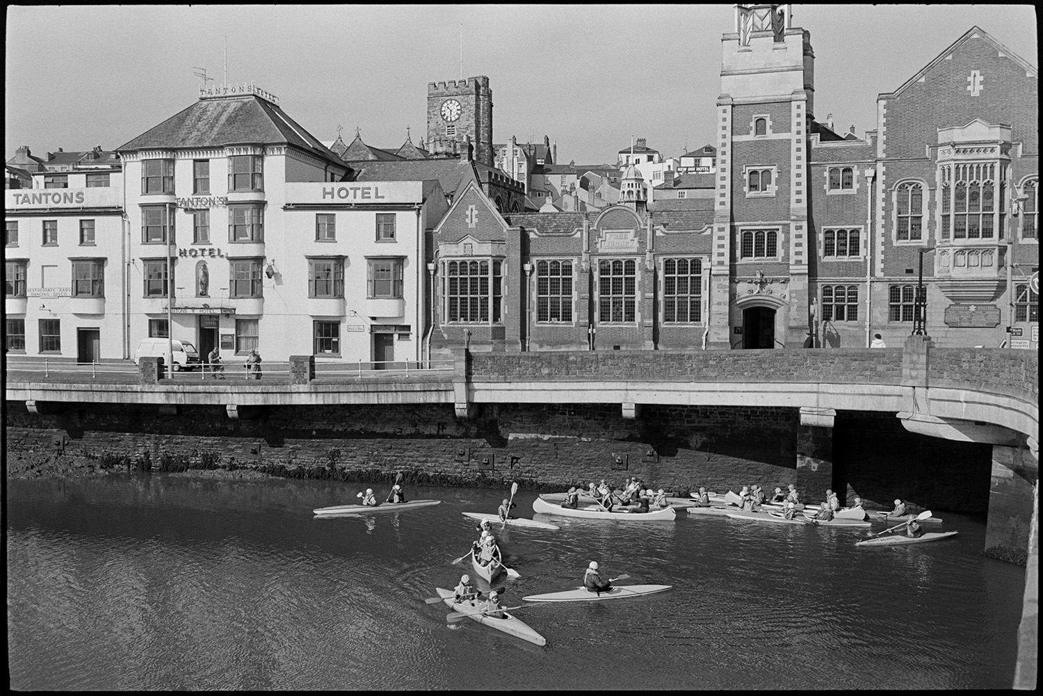 Canoeists on river, quayside capsized canoe! Houses on waterfront. <br />
[People canoeing on the River Torridge by Bideford Long Bridge, also known as Bideford Old Bridge. Building can be seen along the waterfront, including Tanton's Hotel.]