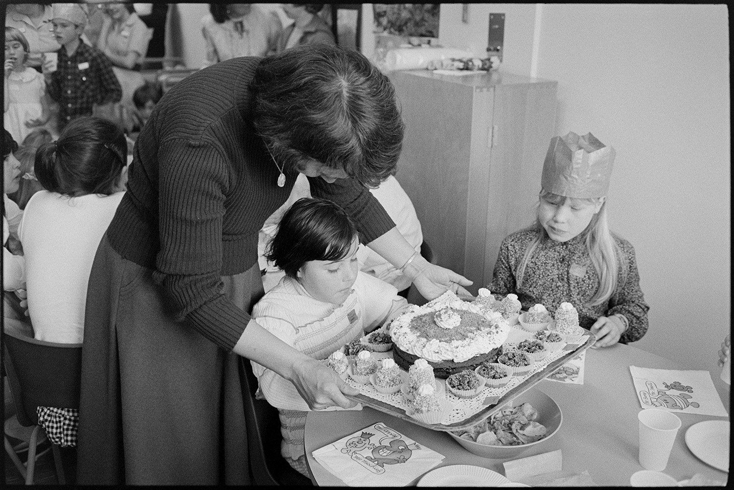 Party in children's ward of Hospital, food and drink served by nurses, buns, cakes. <br />
[A woman serving cake to two children at a party on the Children's Ward at Barnstaple General Hospital.]
