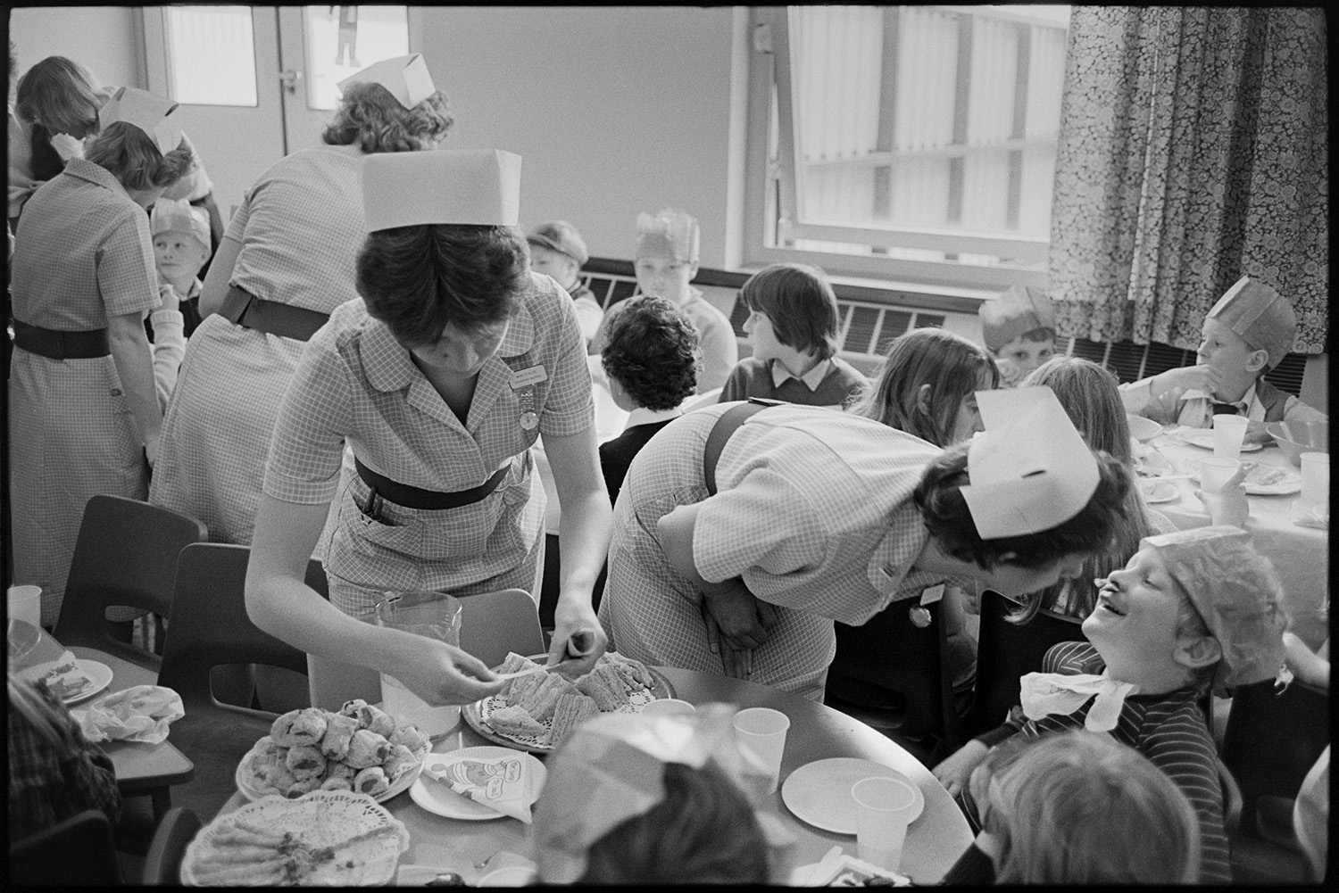 Party in children's ward of Hospital, food and drink served by nurses, buns, cakes. 
[Nurses serving cakes and sandwiches to children at a party on the Children's Ward at Barnstaple General Hospital.]