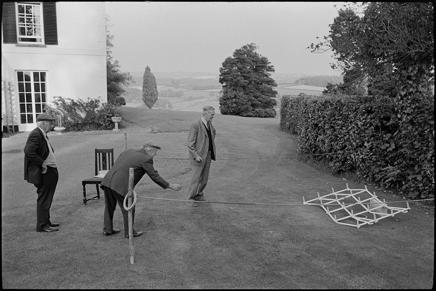Sideshows at garden fete, bowls, hoop la, billiards, golf.
[Three men playing hoop-la on the lawn at a fete at the Old Rectory, Merton with distant views of the countryside and trees in the background.]