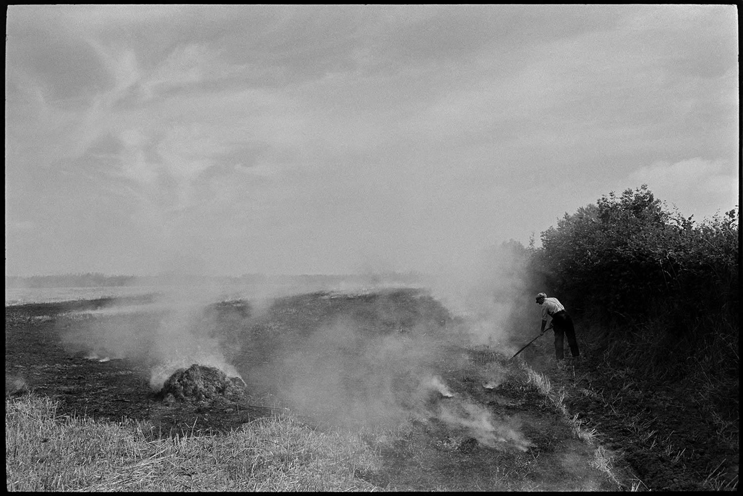 Farmer burning stubble. 
[Alf Pugsley burning crop stubble in a field at Lower Langham, Dolton. Smoke is rising from the burnt areas.]