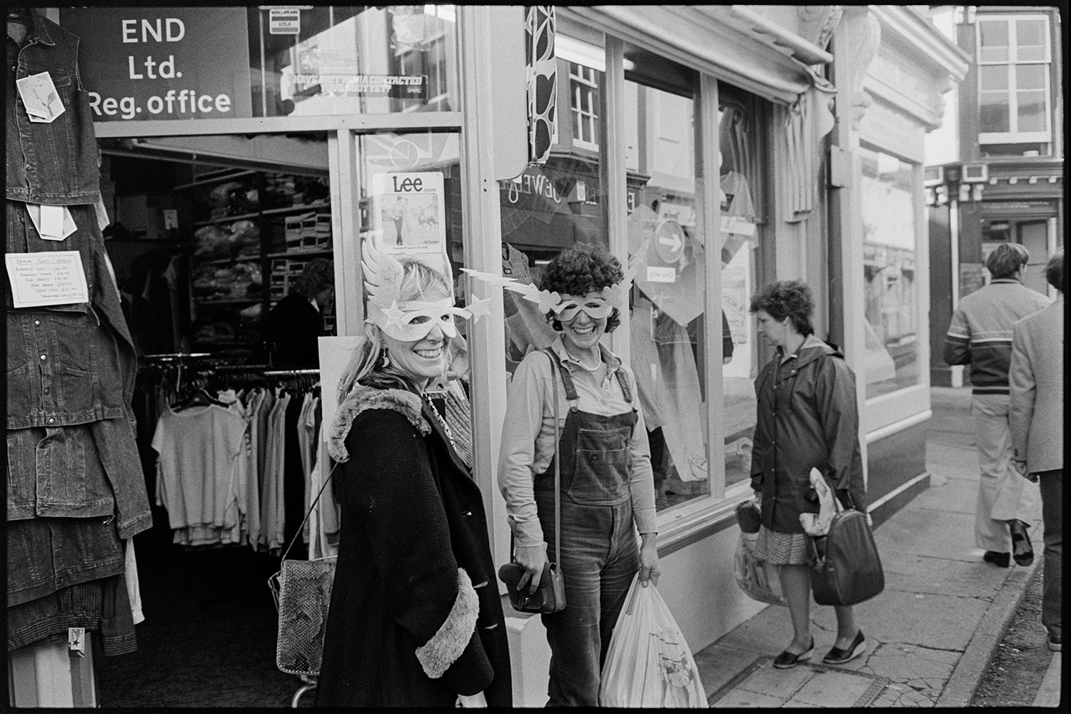 Two women Hooray Henriettas wearing masks while shopping. 
[Two women wearing masks while shopping in Bideford. They are stood outside a clothes shop.]