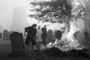 The Friend family burning rubbish in the churchyard by James Ravilious