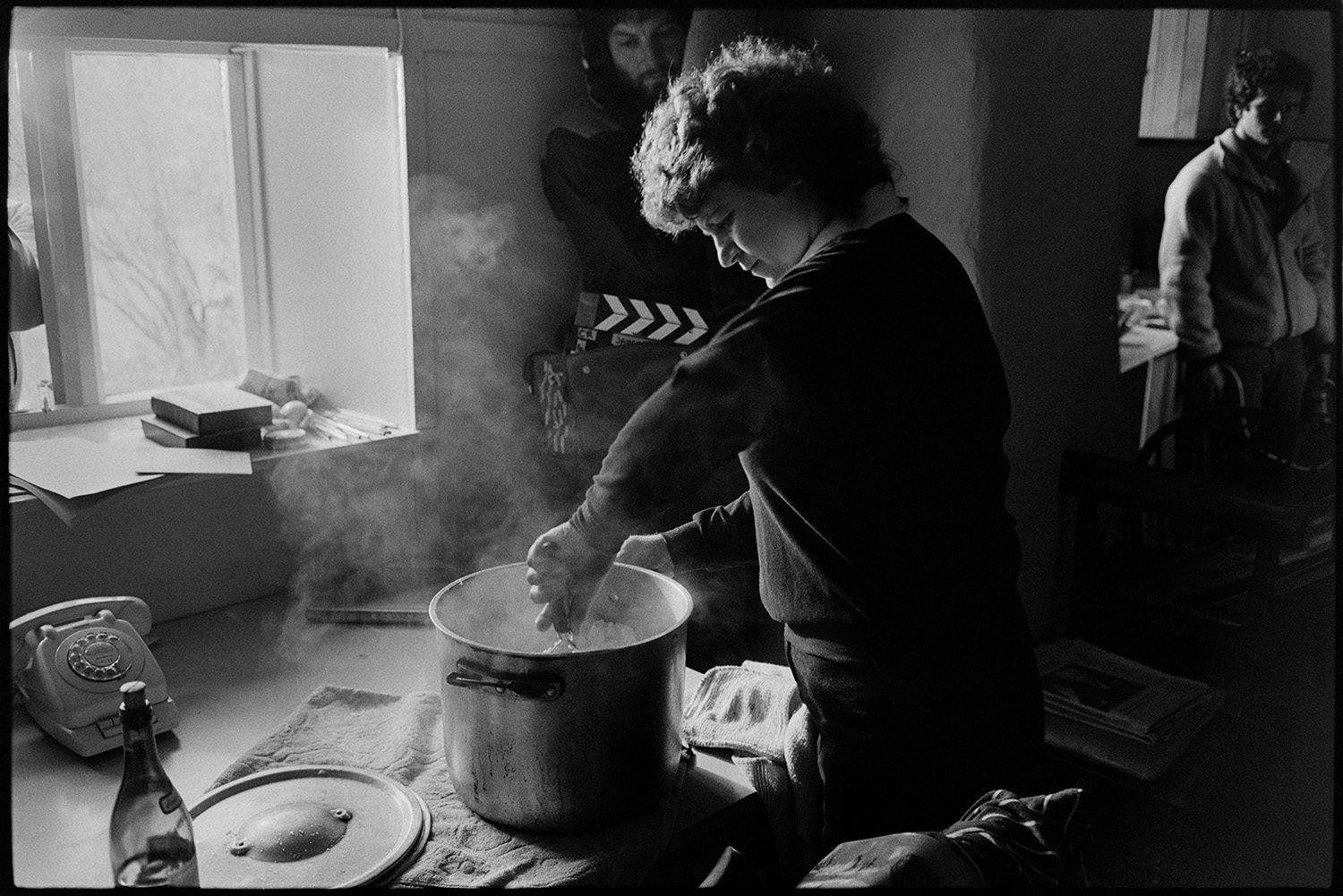 Television film crew filming in hotel kitchen, from BBC.
[A woman mashing potato in a large saucepan in the kitchen at the Duke of York, Iddesleigh, with a cameraman filming her.]