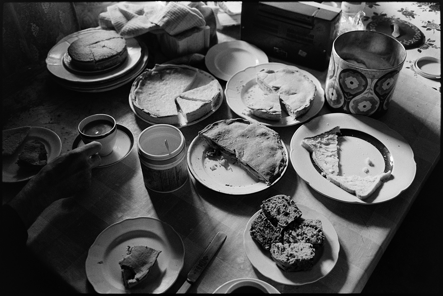 Food and drink laid out on table in farmhouse. Pies and cake.
[Wilfie Spiers' kitchen table spread with bread and butter, cakes, pies and biscuits at Mount Pleasant, Beamsworthy.]