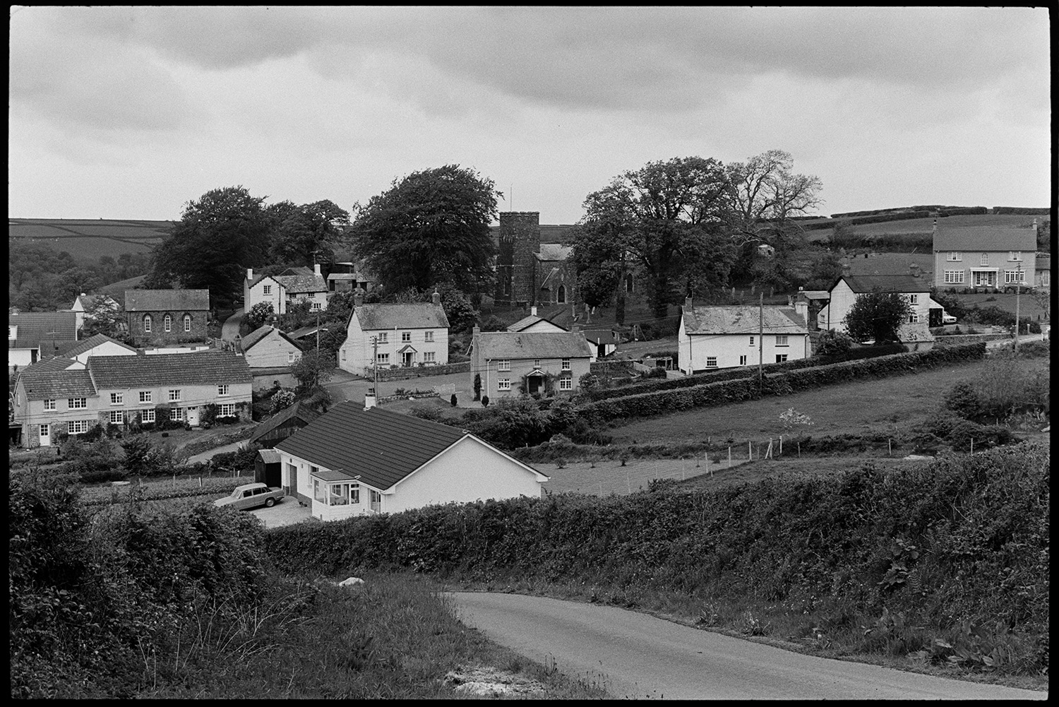 Village and farm, comparison with old photo.
[A view of Meshaw taken from an opposite hillside. The church, chapel and houses are visible.]