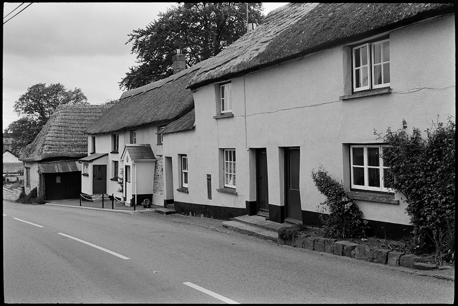 Village and farm comparison with old photo.
[Thatched cottages along a roadside in Meshaw.]