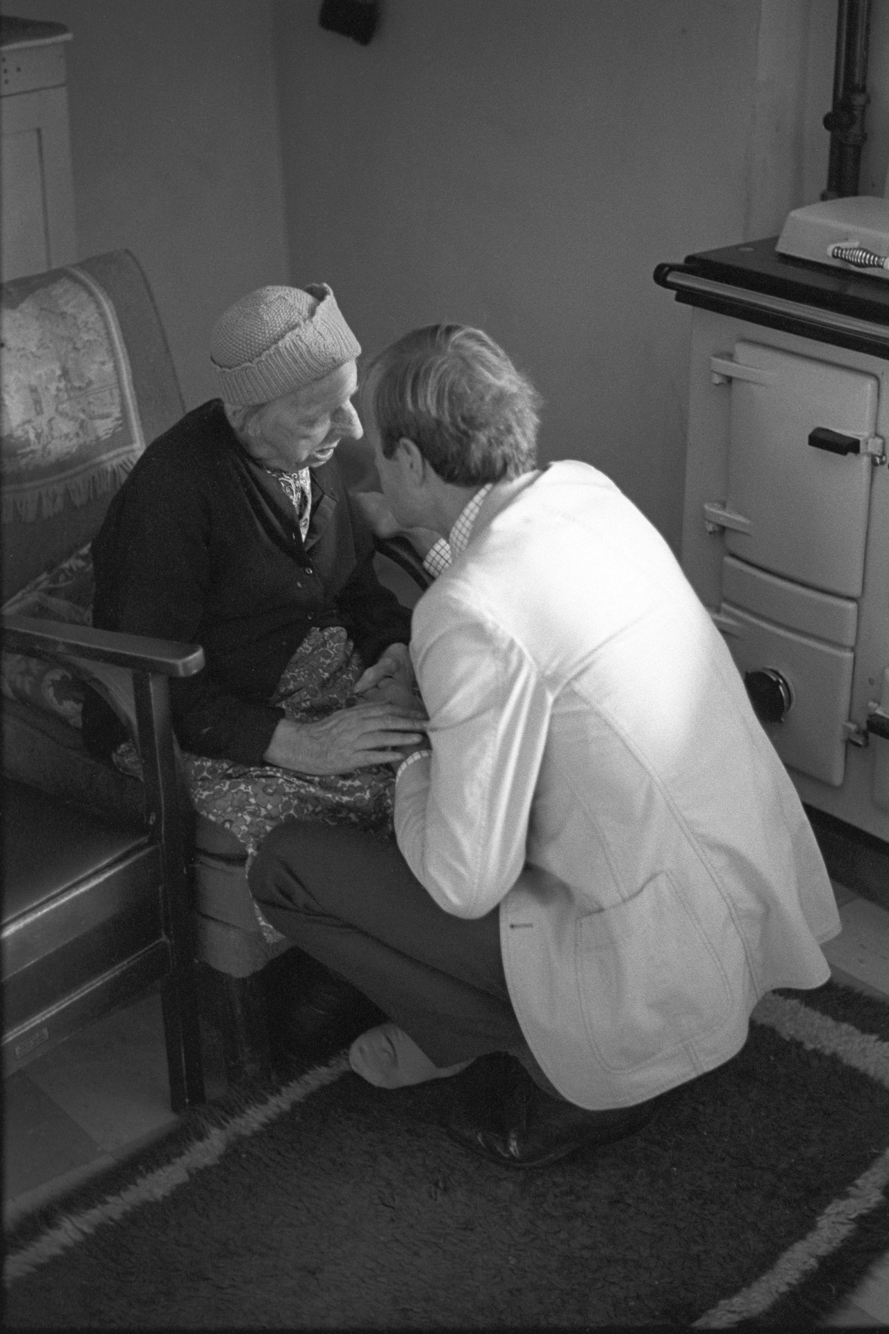 Doctor visiting elderly woman blind and in her nineties, but read braille. <br /> [Doctor Richard Westcott visiting Lizzie Symons at her home near Warkleigh. He is talking to her in front of an Aga or rayburn stove. She is blind and over ninety years old.]