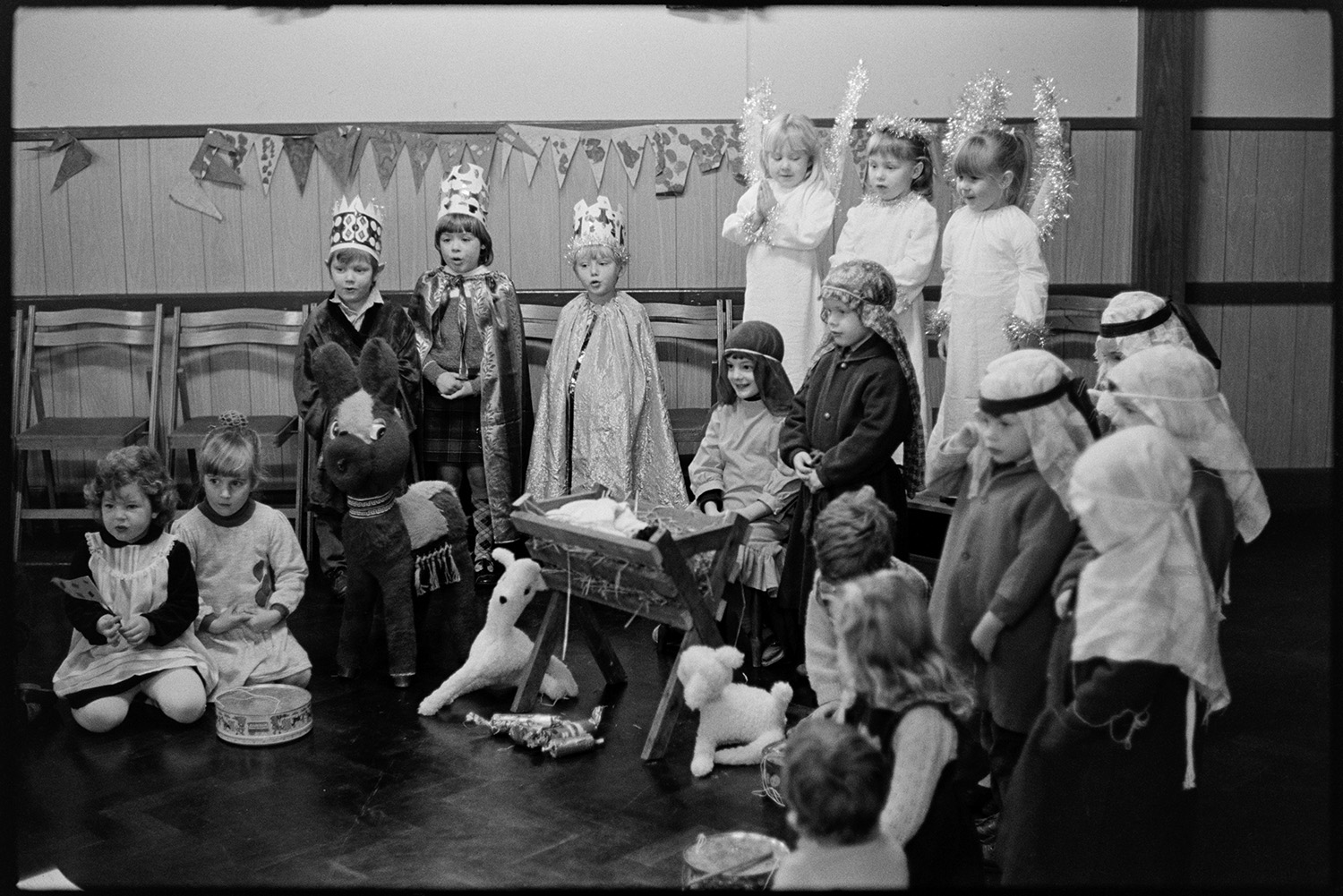 Christmas, children's Nativity play, singing carols.
[Children in costume performing a Christmas Nativity play in the village hall at Dolton. They are singing a carol.]