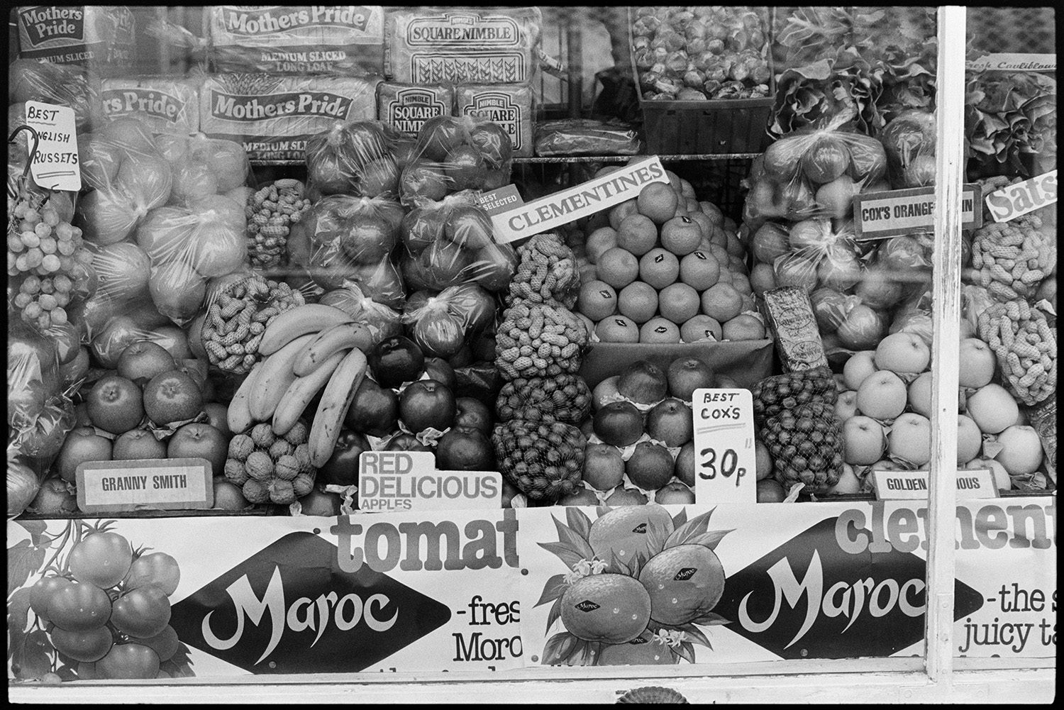 Fruit and nuts displayed in shop window.
[Fruit, including apples, oranges and bananas, alongside packaged bread and bags of various nuts are displayed in a shop window in Barnstaple. A sign for Maroc fresh produce is in the front of the window.]