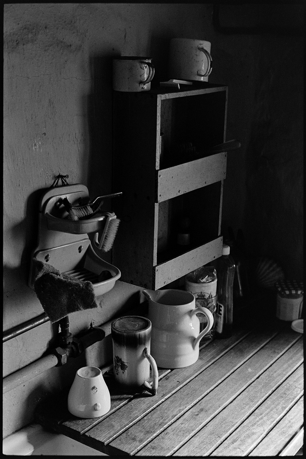 Interior of kitchen, gas boiler, utensils etc. 
[The interior of the kitchen at Bottreaux Mill, Molland with jugs and brushes on a wooden worktop next to a sink.]