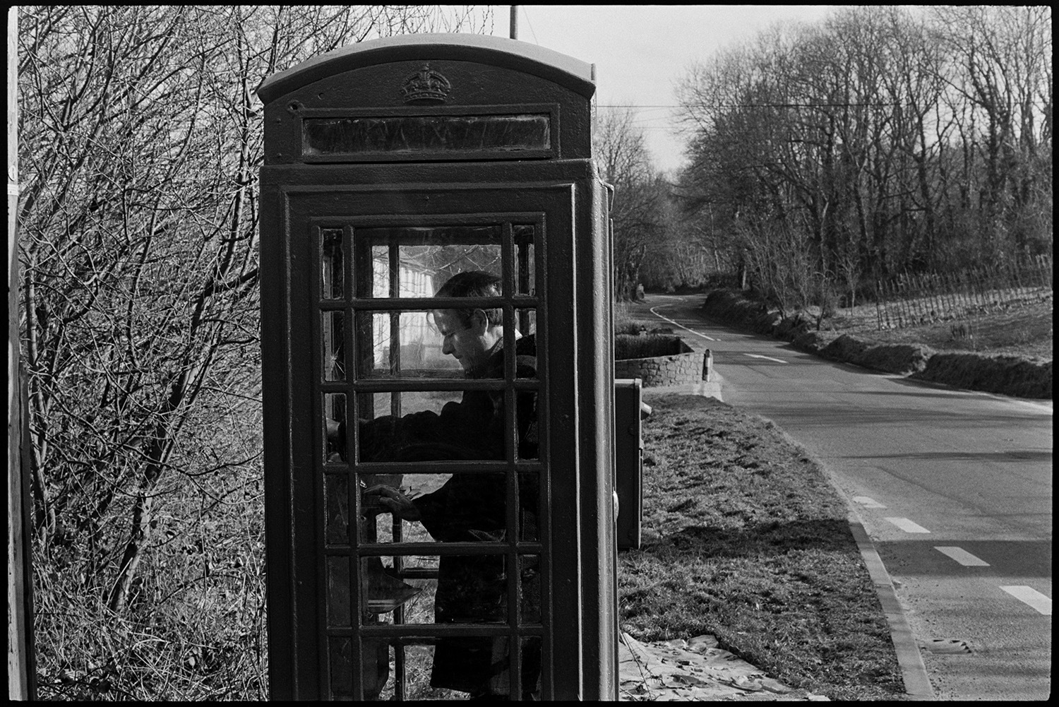 Doctor in telephone kiosk making call after being bleeped. 
[Doctor Richard Westcott making a call in a telephone box on a road near South Molton after being paged.]