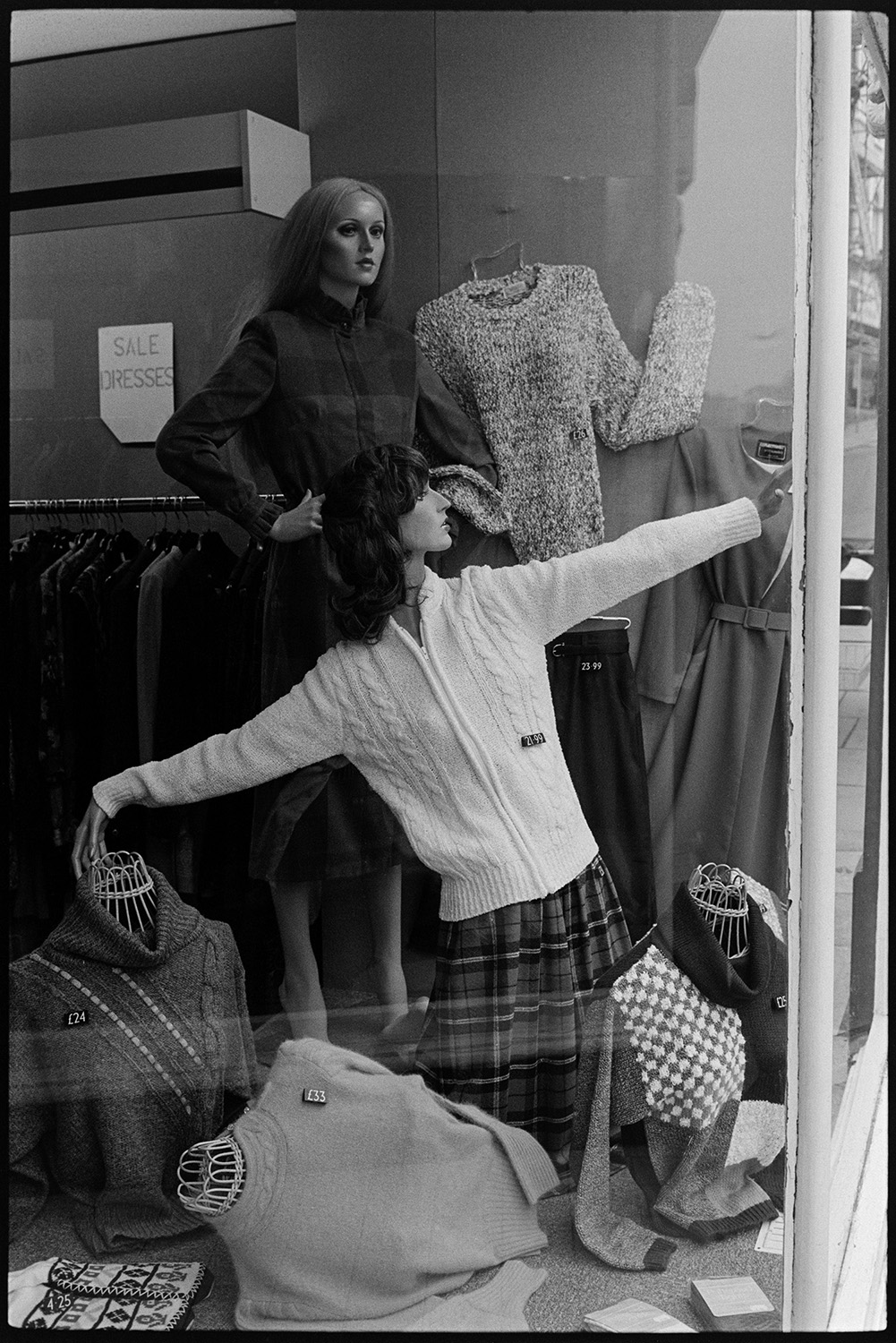 Dummies in clothes shop window. 
[Two mannequins modelling women's clothes in a clothes shop window in Barnstaple. They are modelling jumpers and skirts.]