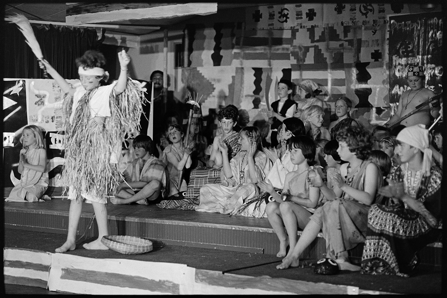 School performance produced by visiting group from Ghana. 
[School children performing a show on a stage in Dolton, possibly at the village hall or school, produced by a group from Ghana.]