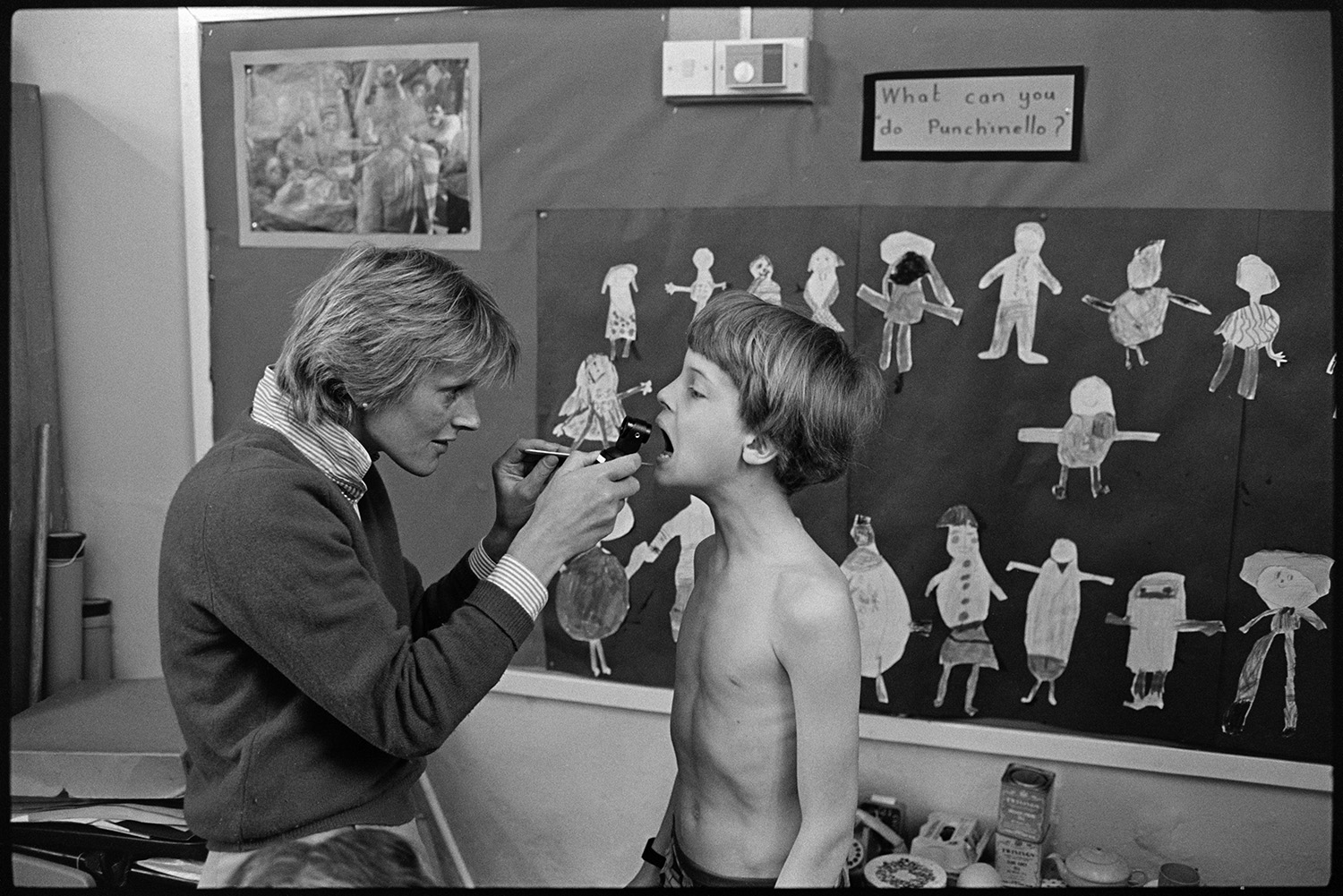 Nurse giving children medical inspection in school. 
[A nurse giving a boy a medical inspection at Dolton Primary School. She is checking his throat.]
