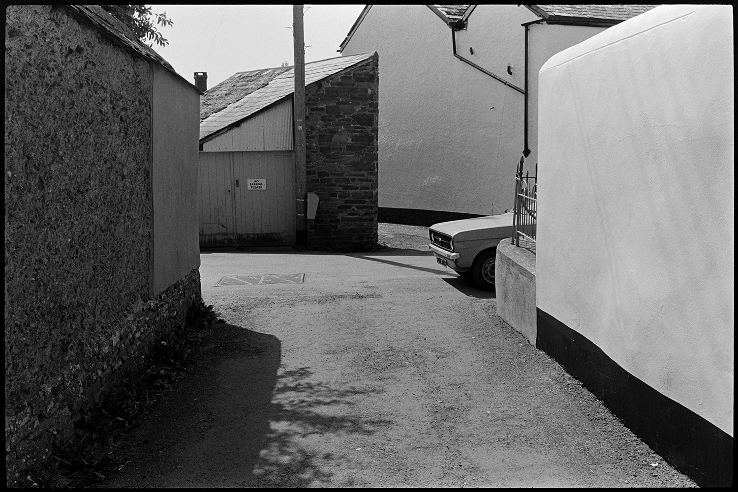 Street scenes. Man and children. 
[A view of houses and walls in North Street, Dolton. A garage at the end of the road junction is visible.]