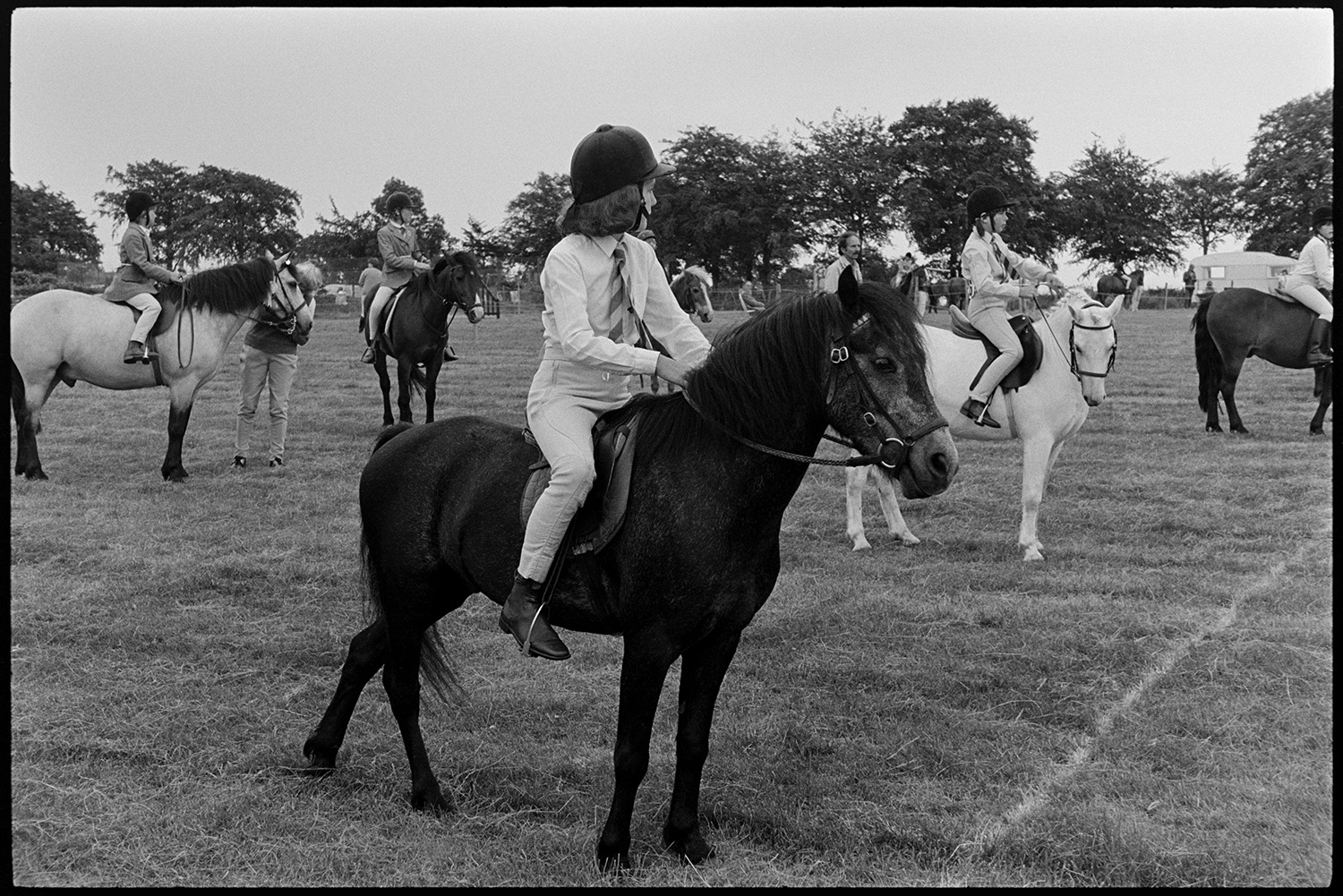 Gymkhana at Fair, horses, ponies and riders. Old bus. 
[Children on horses getting ready to compete in an event at the gymkhana at Winkleigh Fair.]