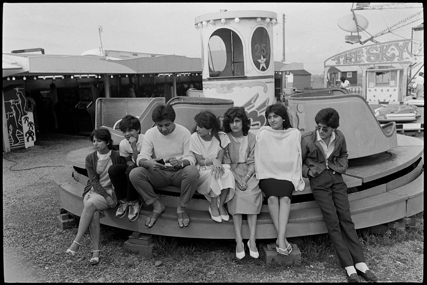 Seaside amusements, children. 
[An Asian family sat on a ride at an amusement park at Westward Ho!.]