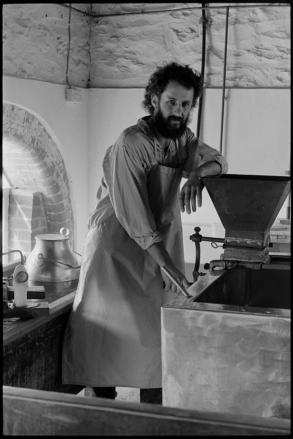 Man making cheese in dairy. 
[Peter Charnley stood by a vat making cheese in the dairy at Park Farm, Umberleigh.]