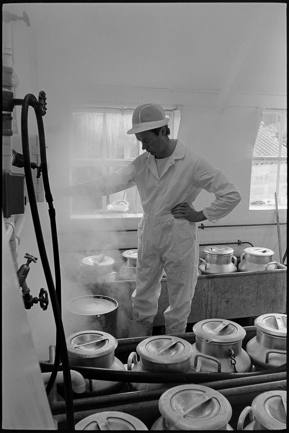 Yoghurt maker in dairy. 
[Peter Duncan making yoghurt in the dairy at Stapleton Farm, Langtree. His stood by rows of milk churns.]