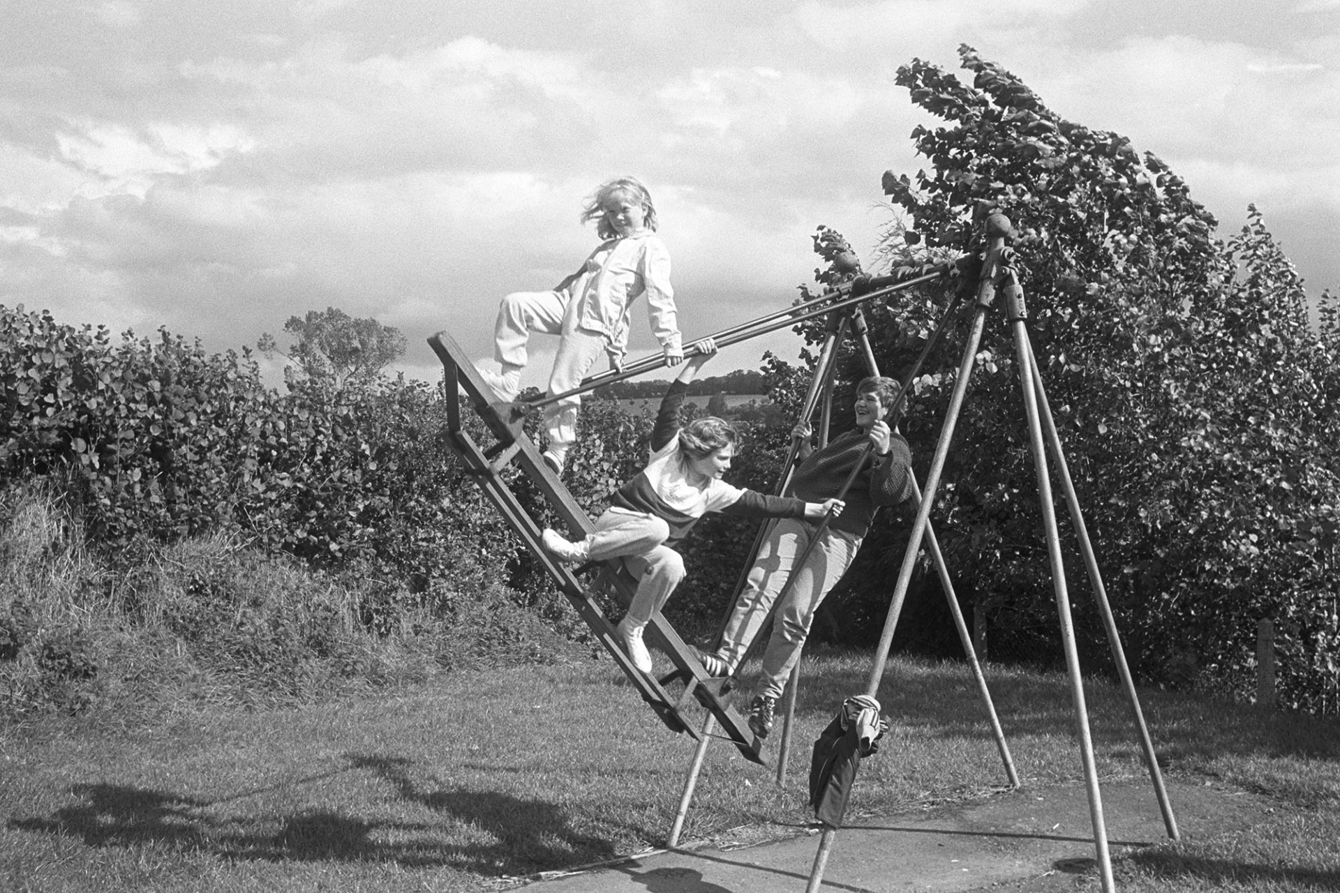 Children playing on swings in public playground. 
[Three children playing on a swing in the playing field at Stafford Way, Dolton. Nicky Squire may be the girl at the top of the swing.]