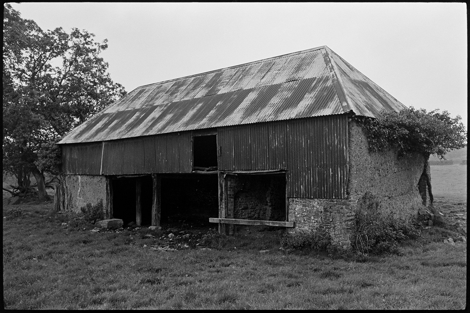 Old cob barn at site of farm. Corrugated iron roof. 
[A cob barn with a tallet and corrugated iron roof in a field at Henacroft, Iddesleigh.