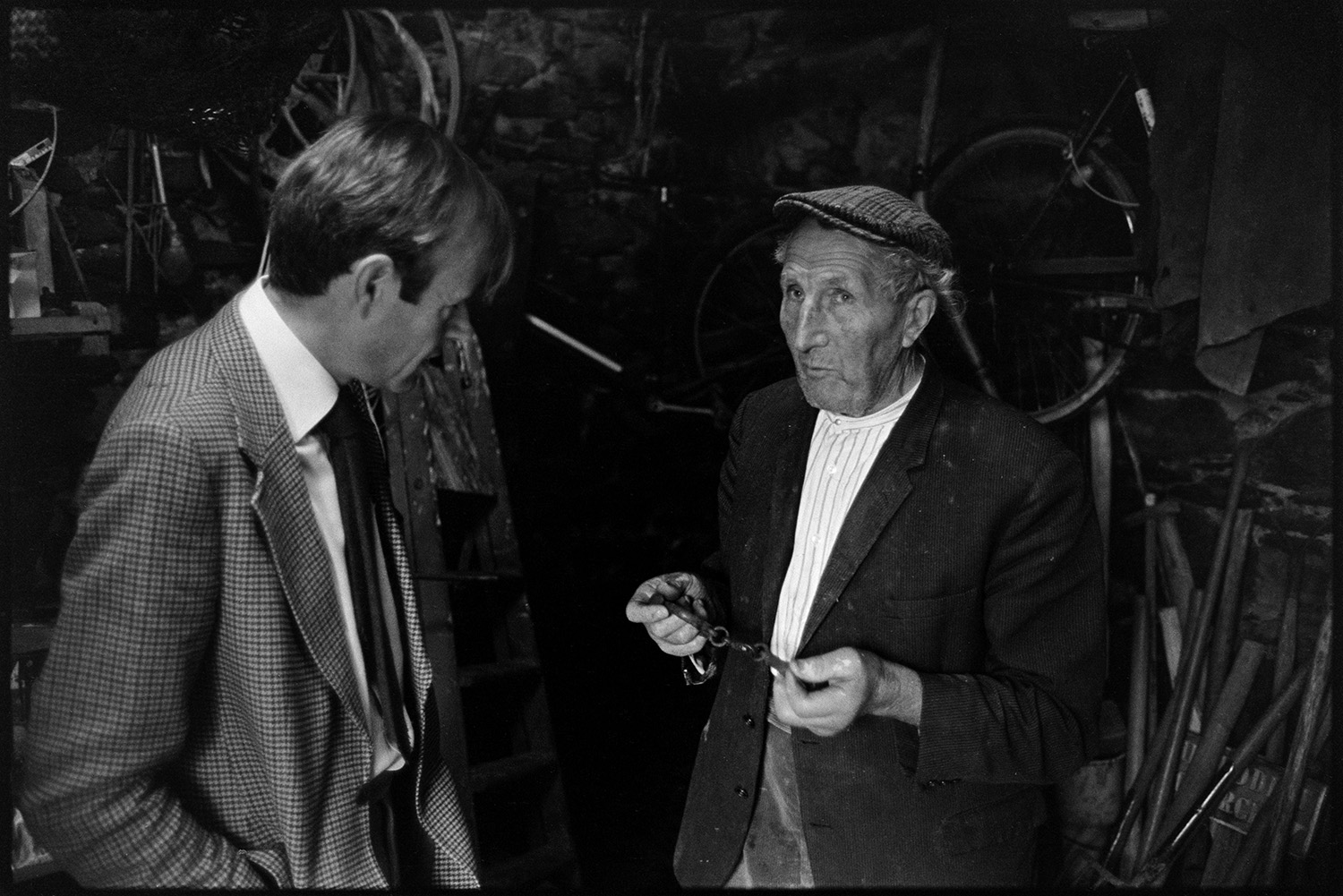 Doctor on rounds talking to man patient outside his house.
[Doctor Richard Westcott talking to Edward Cotsford in a shed at his house at Charles Bottom, South Molton. Various tools and a wooden ladder can be seen in the shed.]