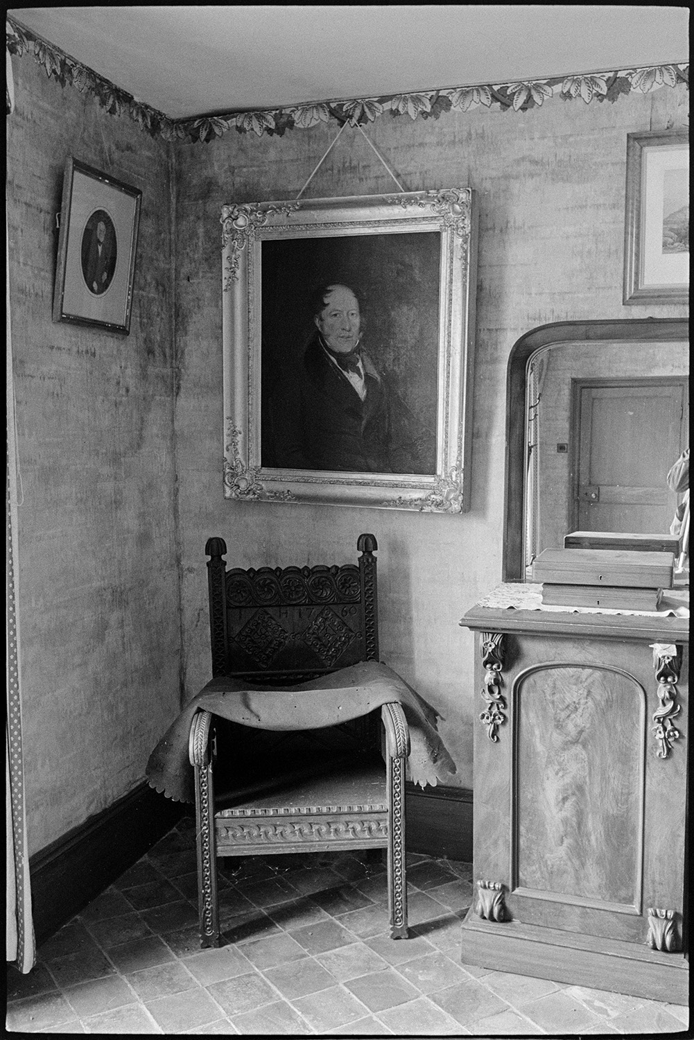 Dining room of large farmhouse. Furniture, table, chairs, mirror on sideboard. 
[A sideboard and carved wooden chair in the dining room at Narracott farm, South Molton. Pictures are also hung on the wall.]