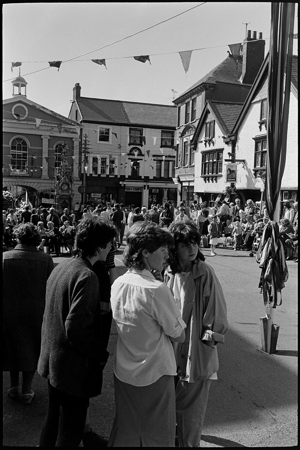 May Fair celebrations, people waiting for start of fair, preparing float. 
[Men and women gathered in Torrington Square waiting for the start of the May Fair. The square is decorated with bunting and a maypole is visible in the foreground.]