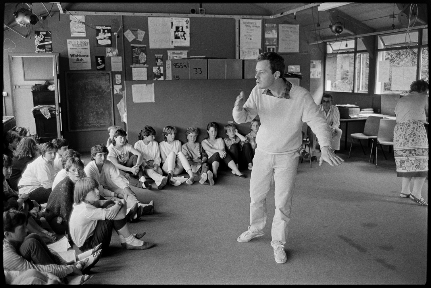 Music class in school, visiting teacher with staff and pupils playing music and advising. 
[Chris Williams teaching a drama lesson to pupils in the drama studio at Holsworthy School. Various lighting equipment is hung up in the room.]