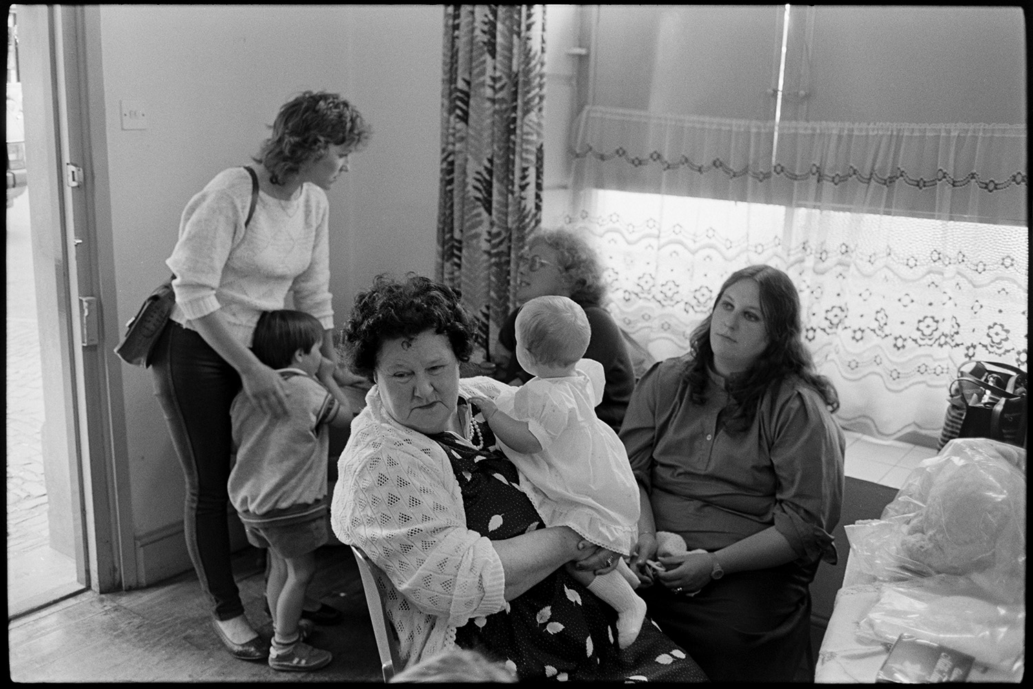Fair. Baby competition, woman judging. Mothers and babies waiting to be judged. 
[Mothers and their babies waiting to be judged in the baby competition in Chulmleigh Town Hall for Chulmleigh Fair.]