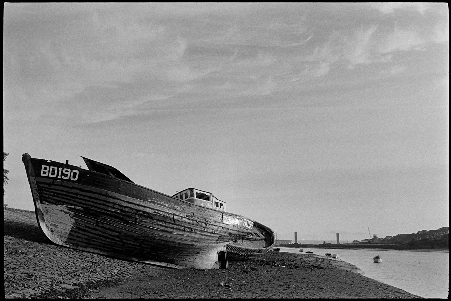 Abandoned wooden fishing boats shortly before they were cut up. The last ? 
[Two wooden fishing boats on the banks of the River Torridge at Bideford before they were cut up. Possibly the last of their kind. The number of the boat in the foreground is BD190. The pillars of Bideford New Bridge under construction can be seen in the background.]