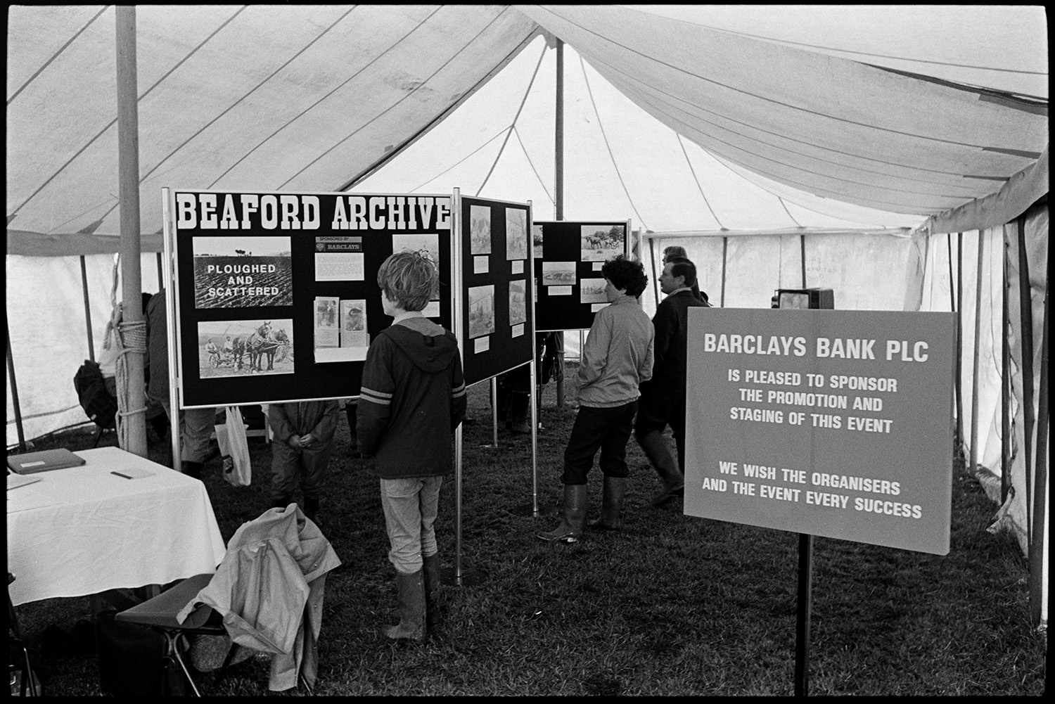 Agricultural show, prize sheep exhibition, TV  tent.
[Visitors to the Beaford Archive exhibition in a marquee at the North Devon Show in Alverdiscott. Exhibition display boards with photographs and a Barclays Bank sponsorship sign are visible.]
