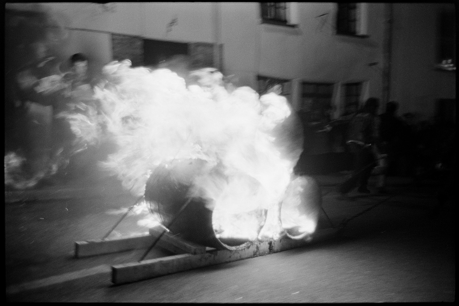 Carnival procession at night with burning torches and blazing tar barrels, floats.
[Two burning tar barrels ablaze on the street during the evening procession at Hatherleigh Carnival.]